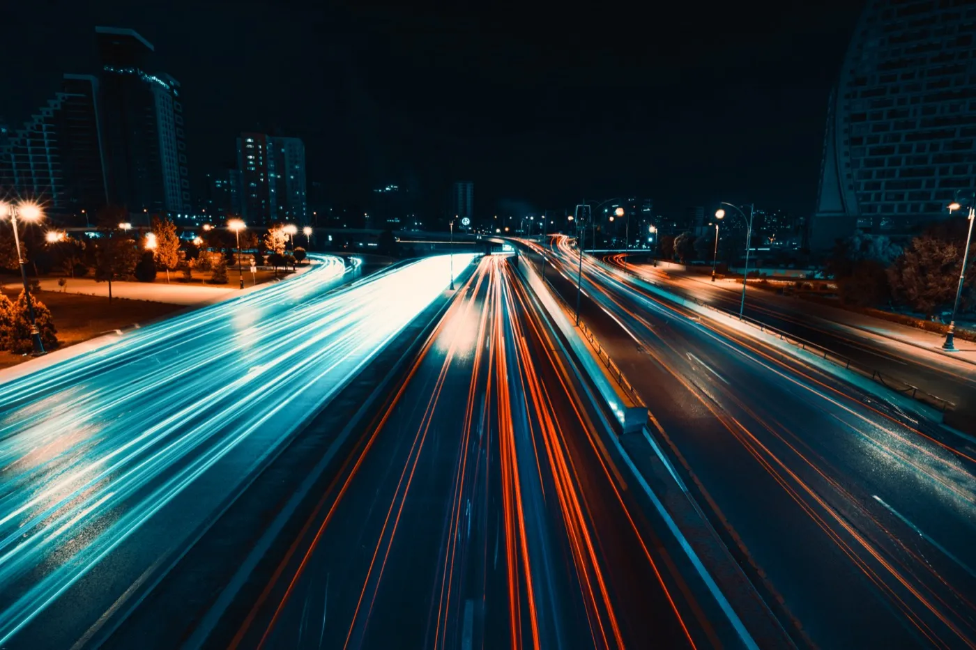 Blue and orange light trails along a city expressway at night