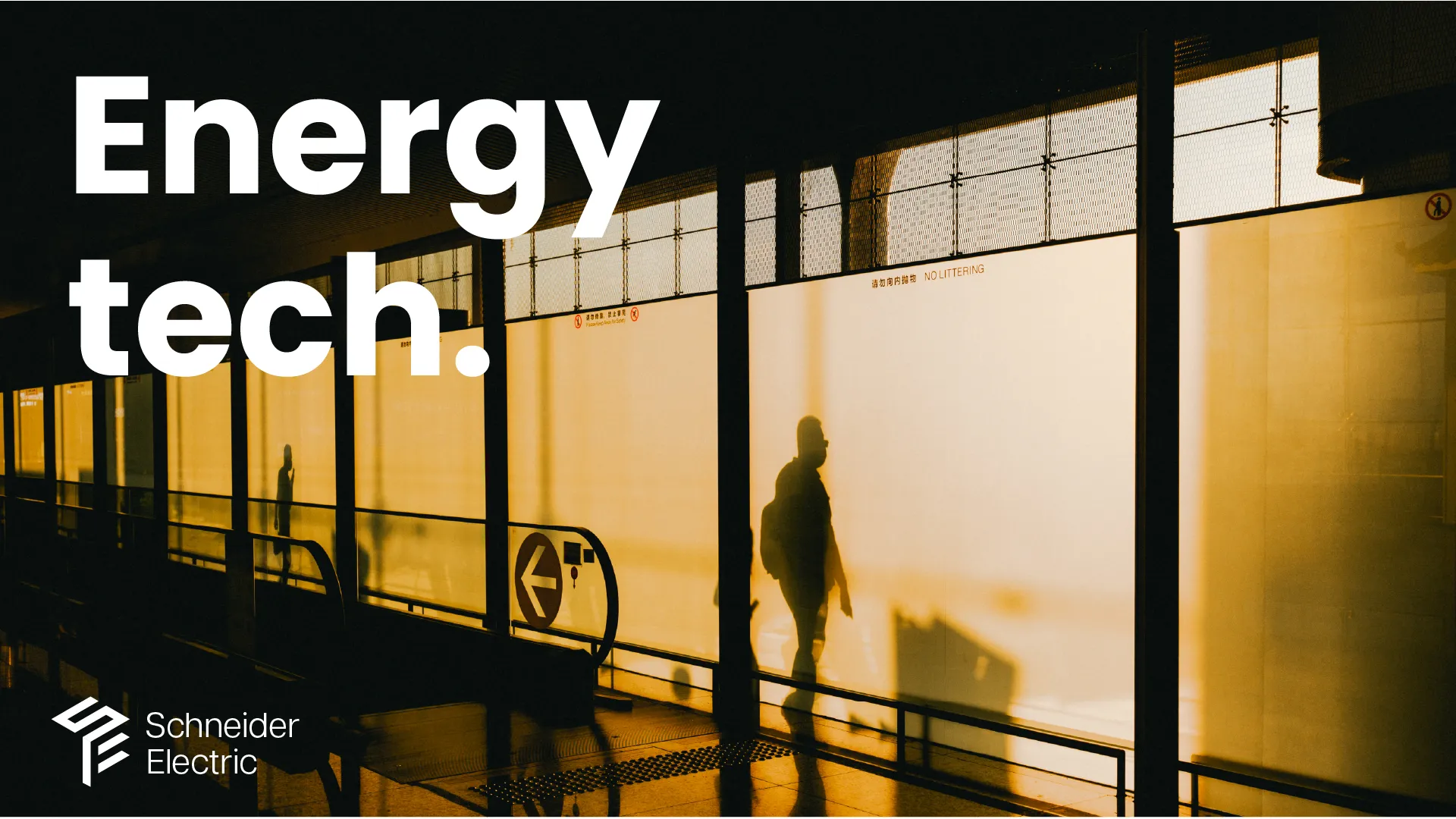 Commuter in silhouette against a backlit station wall, warm amber