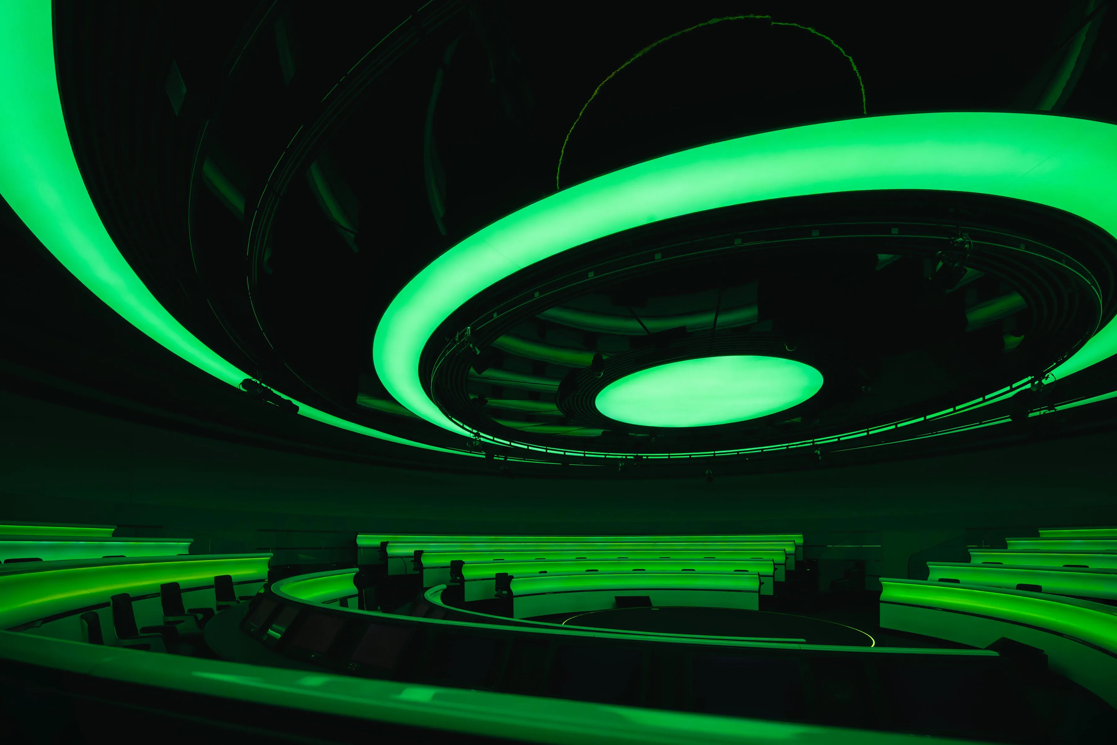 Empty Mission Control room lit entirely in green