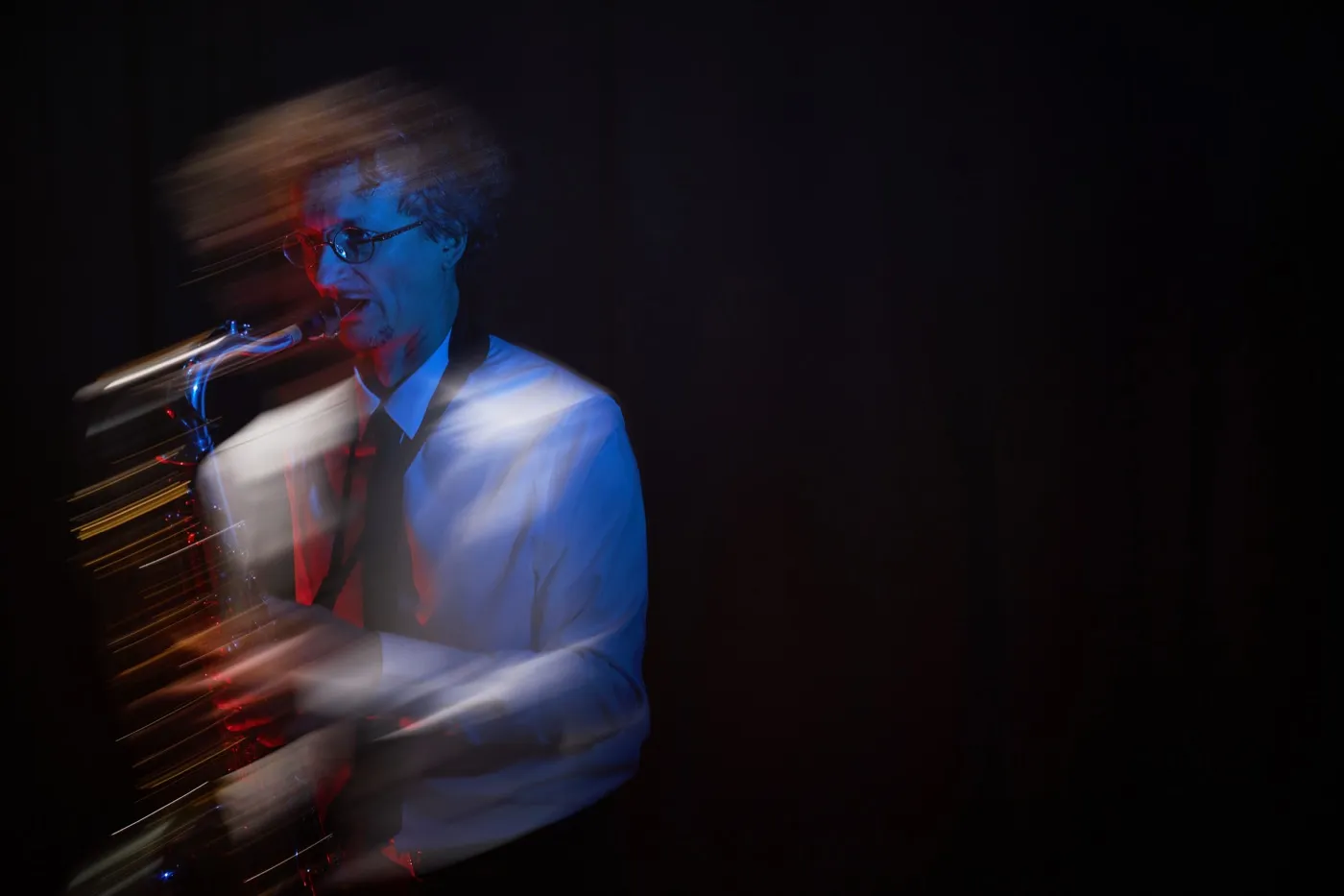 Long-exposure photograph of a saxophonist, the movement smeared into light